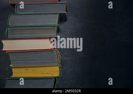 Stack of old battered books on retro photos against background concrete wall Stock Photo