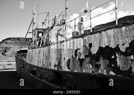 A grayscale shot of an old boat on the beach Stock Photo