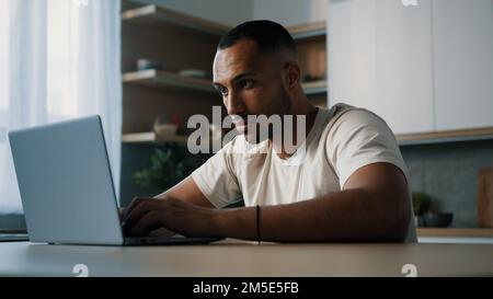 Mad sad unhappy panic male looser African millennial man guy American user freelancer worker gamer at home kitchen work with laptop lost failure Stock Photo