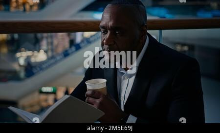 Ethnic male African man businessman employer entrepreneur drinking tea aromatic hot coffee at table in cafe cafeteria restaurant drink latte Stock Photo