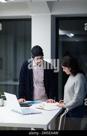 Two young colleagues discussing and taking notes in the office Stock Photo