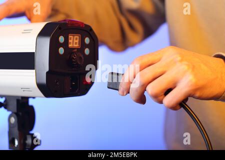 a person in the background inserting a power cord into a studio flash Stock Photo