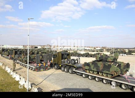 Bundeswehr Heavy Equipment Transport Systems (HETS) carrying American Bradley Fighting Vehicles (BFVs) are staged and inspected for onward movement at Coleman Barracks, Germany on March 7, 2022. The Bundeswehr work side‐by‐side with American partners to support the Army Prepositioned Stock program, help assure our Allies and deter Russian aggression. Stock Photo