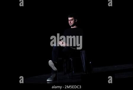 Kiev, Ukraine December 9, 2018: A man sits on the stage and looks at the phone on a black background Stock Photo