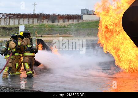 Firemen from the Shreveport Fire Department work together to hold and control a hose as part of a required training exercise at Barksdale Air Force Base, Louisiana, Mar. 9, 2022. The Shreveport Fire Department firefighters work with firefighters from the 2nd Civil Engineer Squadron to practice aircraft crash fire extinguishing techniques. Stock Photo