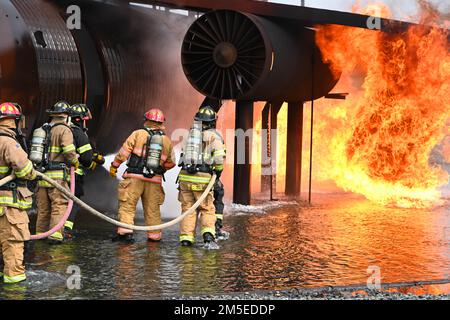 Firefighters from the 2nd Civil Engineer Squadron and Shreveport Airport Firemen use hoses to push back a fire at Barksdale Air Force Base, Louisiana, Mar. 9, 2022. The firefighters start by pushing the ground fireout of the way then extinguish the fire from the source. Stock Photo