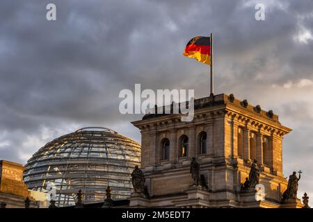 Dome of Reichstag Building and National flag of Germany at sunset in city of Berlin, Germany. Stock Photo