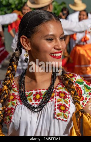 An attractive young dancer in traditional dress from San Juan Cacahuatepec during Guelaguetza in Oaxaca, Mexico.  She is wearing the typical hand cros Stock Photo