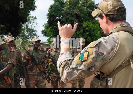 A U.S. Army Green Beret assigned to Special Forces Operational Detachment Alpha (SFOD-A) 3212, 3rd Special Forces Group (Airborne) discusses contact drills and squad movement techniques with Beninese soldiers from the 1st Commando Parachute Battalion in Ouassa, Benin, March 08, 2022. U.S. engagement comes with mutual benefit, upholds international norms, and treats partners as equals. Stock Photo