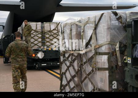 Senior Airman Stephen Holpuch, 39th Airlift Squadron loadmaster (left), and Tech Sgt. Anthony Como, 7th Logistics Readiness Squadron air terminal function load planning NCO in charge (right), standby as additional pallets come into the C-130J Super Hercules at Dyess Air Force Base, Texas, March 8, 2022. The pallets contain a dehydrated rice casserole, which will be shipped in support of future humanitarian efforts of the Denton Cargo program. Stock Photo
