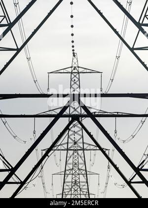 View down a line of electricity pylons in the fens, Norfolk, England, UK Stock Photo