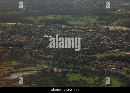 An aerial shot of green fields, buildings and roads during daytime  from the point of view of a plane Stock Photo