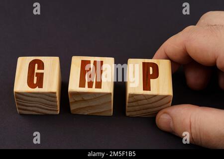 Business concept. On a black surface, a man puts cubes with the inscription - GMP Stock Photo