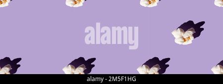 Delicious popcorn on a purple background. Seamless pattern. Banner. Culture of cinema ,domestic leisure with friends . Stock Photo