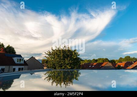 Autumn image of the anvil of a thunderstorm with tree reflected in the glass of a skylight Stock Photo