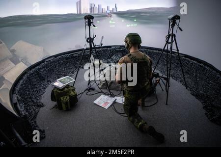 A 1st Lt. tactical air control party specialist with the German Air Force conducts simulated ground forces toward a location based on information fed from instructors to his headset during a training evaluation in the Advanced Joint Terminal Attack Control Training Simulator (AAJTS) at Will Rogers Air National Guard Base, Oklahoma City, Jan. 24, 2022. The training conducted by the 137th Combat Training Flight, Oklahoma Air National Guard brought together the NATO partner nations of the Czech Republic, Germany and the U.S. for a five week course that qualifies students as joint terminal attack Stock Photo