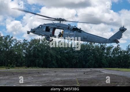 220310-N-FA490-1592 YIGO, Guam (Mar. 10, 2022) – An MH-60S Sea Hawk helicopter, attached to the “Wildcards” of Helicopter Sea Combat (HSC) Squadron 23, practices a prepared landing for pilot proficiency, during search and rescue training. Attached to Destroyer Squadron (DESRON) 7, HSC-23 is on a rotational deployment to the U.S. 7th Fleet area of operations in support of security and stability in the region, and to work alongside allied and partner navies to provide maritime security and stability, key pillars of a free and open Indo-Pacific. Stock Photo