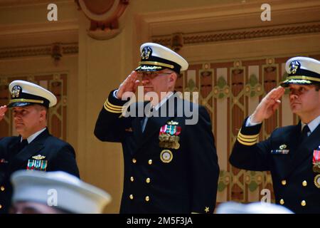 220310-N-RB168-0304 PITTSBURGH, Pa. (March 10, 2022) Cmdr. Christopher McCurry, from Aloha, Oregon, center, renders a salute during the national anthem. McCurry relieved Cmdr. Brandon Smith, right, as commanding officer of Navy Talent Acquisition Group (NTAG) Pittsburgh, during the change of command ceremony at the historic Soldiers and Sailors Memorial Hall and Museum. Capt. Katrina Hill, commodore of Navy Recruiting Region East, officiated the transfer of command as the presiding officer. NTAG Pittsburgh, part of Navy Recruiting Command, recruits the next generation of Navy Sailors throughou Stock Photo