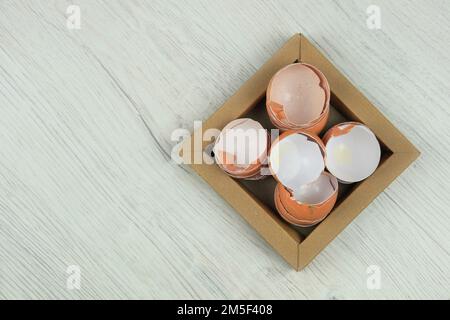 Pile of cracked broken eggshells on carton plate. Organic waste for compost. Top view. Copy space. Stock Photo
