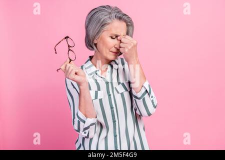 Photo of tired upset lady wear smart casual clothes holding spectacles having headache isolated pink color background Stock Photo