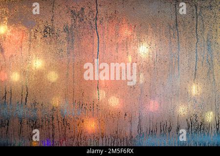 Selective focus photo. Rain drops on window and lights at background. Stock Photo
