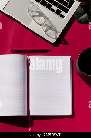 flat lay composition of empty notebook, coffee, computer and glasses on magenta background  Stock Photo