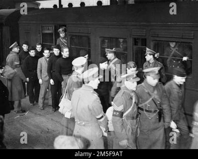 German PoWs are escorted from their train carriage and along the platform at a London station (possibly Euston) by British Military Police.  These prisoners are U-boat crew and are being transferred from one camp to another.