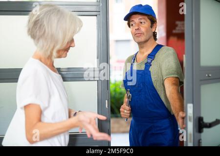 Skilled male plumber talking with woman homeowner Stock Photo