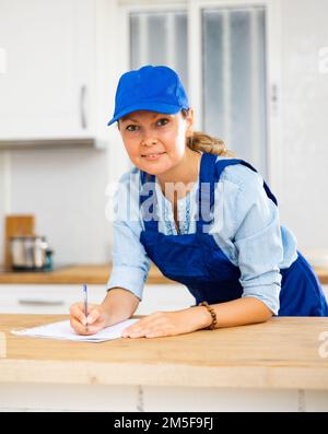 Woman house cleaner making notes in kitchen Stock Photo