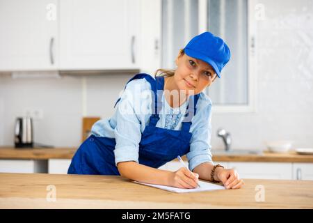 Woman house cleaner making notes in kitchen Stock Photo