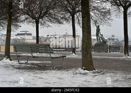 Empty bench in winter in Buerkliplatz Zurich placed on the bank of Lake Zurich and surrounded by trees. Stock Photo