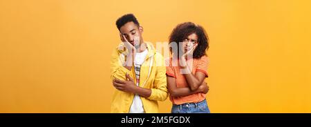 Girl feeling displeased and offended on boyfriend who fell asleep during date pursing lips frowning looking up while boyfriend leaning head on face Stock Photo