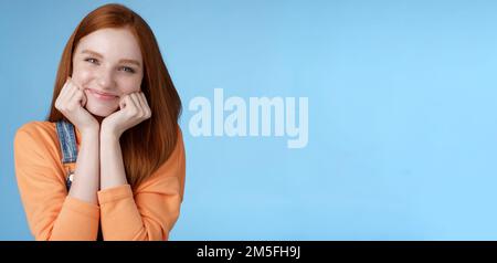 Tenderness, wellbeing, beauty conept. Attractive young ginger girl pure skin blue eyes lean palms silly smiling camera look amused enthusiastic listen Stock Photo