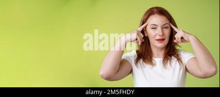 Smart choice. Intrigued thoughtful good-looking assertive redhead creative middle-aged woman touch temples squinting pondering info thinking use Stock Photo