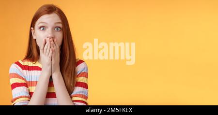 Shocked speechless impressed sensitive redhead european girl reacting stunning rumor gossiping find out secret gasping cover mouth palm stare camera Stock Photo