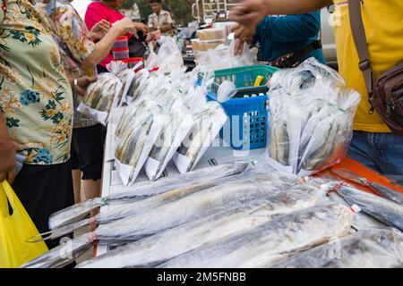 Fresh fish packed in clear bags laying on the table at the local food stall are being picked up by many customers. Stock Photo