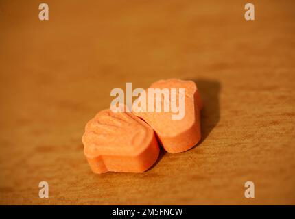 Orange pills with mdma ecstasy dope rolex drug close up background fine art in high quality prints Stock Photo