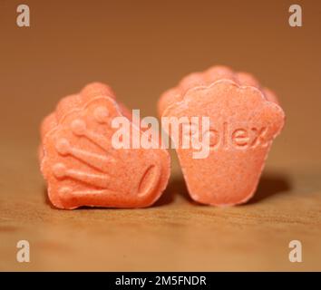 Orange pills with mdma ecstasy dope rolex drug close up background fine art in high quality prints Stock Photo