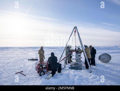 BEAUFORT SEA, Arctic Circle (March 14, 2022) – Members of Naval Undersea Warfare Center Newport and Arctic Submarine Laboratory drill a hole in the ice to prepare for retrieving a test torpedo during Ice Exercise (ICEX) 2022. ICEX 2022 is a three-week exercise that allows the Navy to assess its operational readiness in the Arctic, increase experience in the region, advance understanding of the Arctic environment, and continue to develop relationships with other services, allies, and partner organizations. Stock Photo