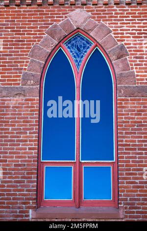 Old Arched Window with Tinted Glass in a Brick Building Stock Photo