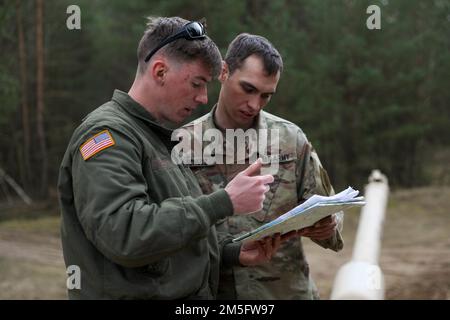 From left, Spc. Austin Zink receives assistance from Staff Sgt. Kyle Schulz both assigned to 2nd Battalion, 34th Armored Regiment, 1st Armored Brigade Combat Team, 1st Infantry Division as they conduct land navigation training at Drawsko Pomorskie, Poland, March 15, 2022. Stock Photo