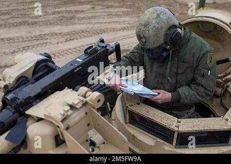Spc. Austin Zink assigned to 2nd Battalion, 34th Armored Regiment, 1st Armored Brigade Combat Team, 1st Infantry Division, reviews his maps before beginning the mounted land navigation training at Drawsko Pomorskie, Poland, March 15, 2022. Stock Photo