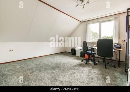 an empty room with a desk and computer on the floor in front of a window that looks out onto the street Stock Photo