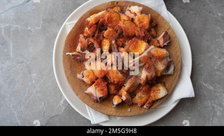 A dish with appetizingly fried pieces of octopus. Top view close-up. Stock Photo