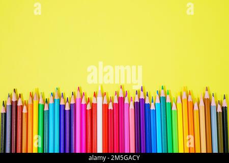 Assortment of colored pencils in various iridescent colors on a yellow background Stock Photo