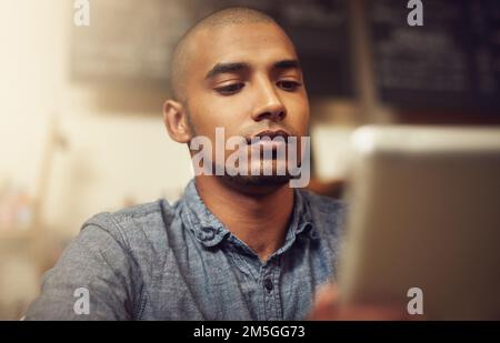 Managing a small business the smart way. a young entrepreneur using a digital tablet in his store. Stock Photo