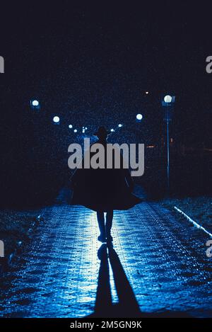 mafia man in a hat and raincoat at night in a rainy city in the style of film noir Stock Photo