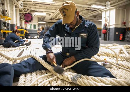 220317-N-TF178-1108    PACIFIC OCEAN (March 17, 2022) – Retail Services Specialist 3rd Class Kojo Brown splices a mooring line aboard amphibious assault ship USS Makin Island (LHD 8), March 17. Makin Island is underway conducting routine operation in U.S. 3rd Fleet. Stock Photo