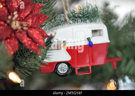 Red and White caravan Christmas tree ornament with a a Christmas tree on its roof and a row of lights hanging along its side Stock Photo