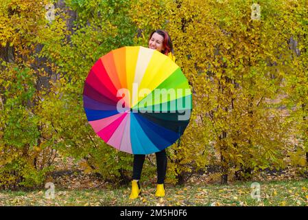 multi-colored huge umbrella and a girl in yellow boots Stock Photo